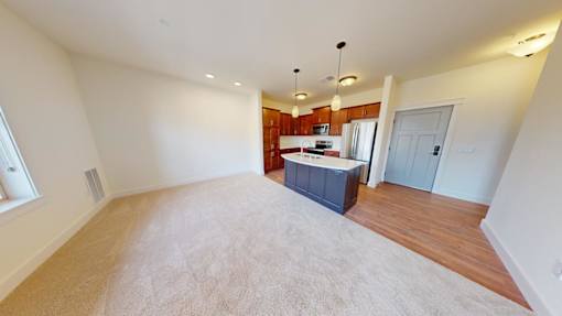A spacious living room with a kitchenette in the background.