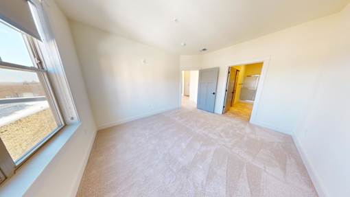 A room with a carpeted floor and a door leading to another room.