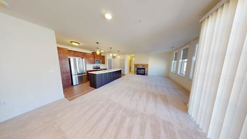 A spacious living room with a kitchen in the background.