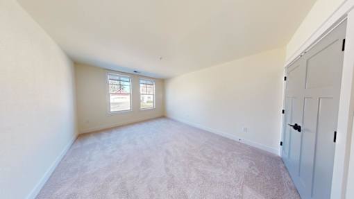 A room with a carpeted floor and a window with blinds.