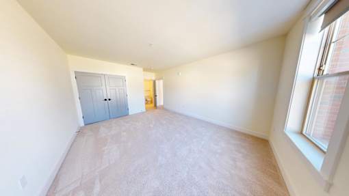 A room with a carpeted floor and a closet with a door.