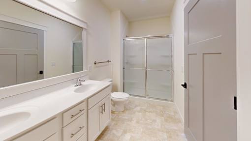 A bathroom with a sink, mirror, toilet, and shower.