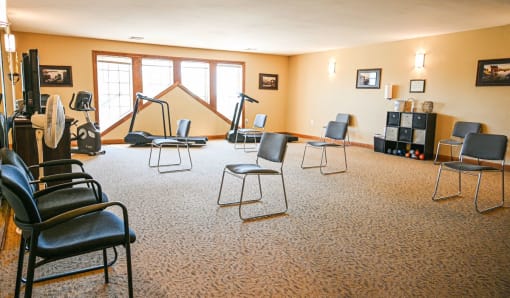 a music room with chairs and a piano and a tripod