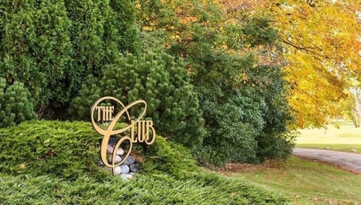 a sign in a grassy area with trees in the background