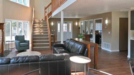 an open living room with leather furniture and a staircase