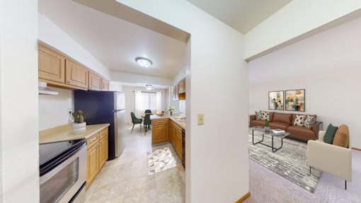 A kitchen with a refrigerator, a dining table with chairs, and a living room with a couch.