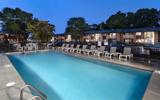 a swimming pool with chairs at night