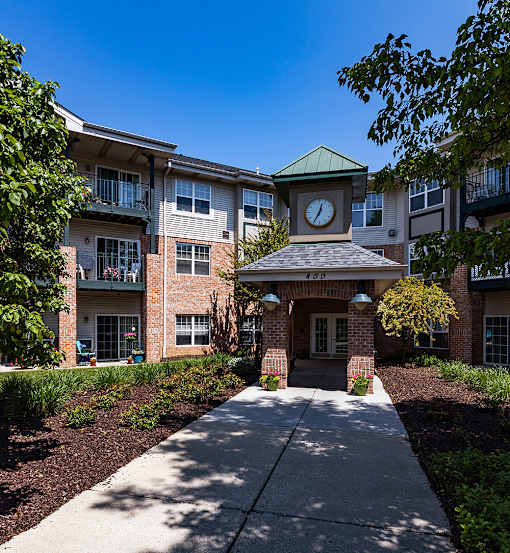 a clock tower in the center of a sidewalk in front of an apartment building