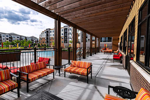 A patio with wooden benches and tables overlooks a body of water.