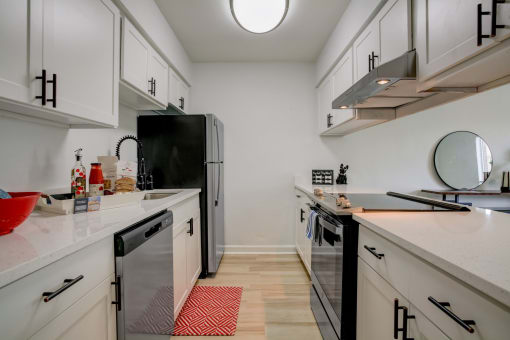 a kitchen with white cabinets and black appliances and a white counter top
