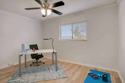 the living room of a home with a desk and a ceiling fan