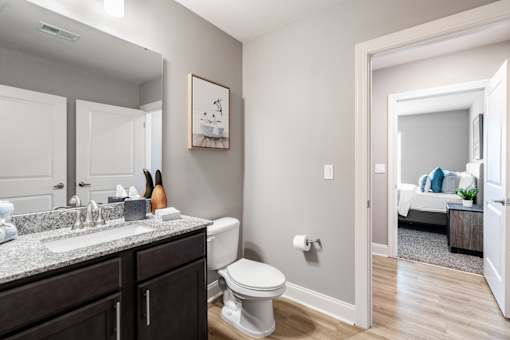 A bathroom with a toilet, sink, and mirror.