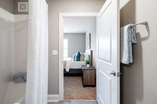 A white door is open to a bedroom with a bed and a nightstand.