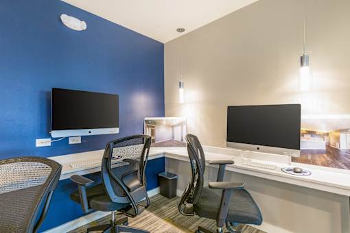 A room with two computer monitors and chairs.