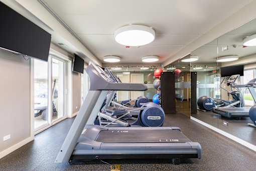 A treadmill is in the middle of a room with mirrors on the wall.