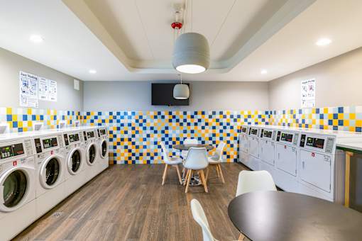 A laundromat with a row of washing machines and a row of dryers.