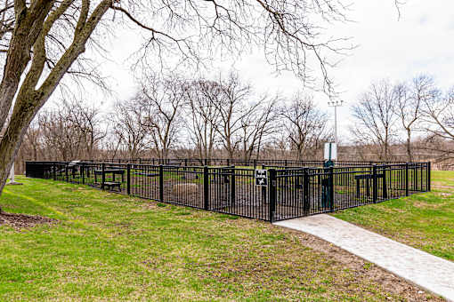 A black fence surrounds a grassy area with a tree and a path.