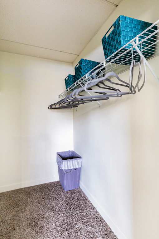A white wall with a shelf and a blue container on it.