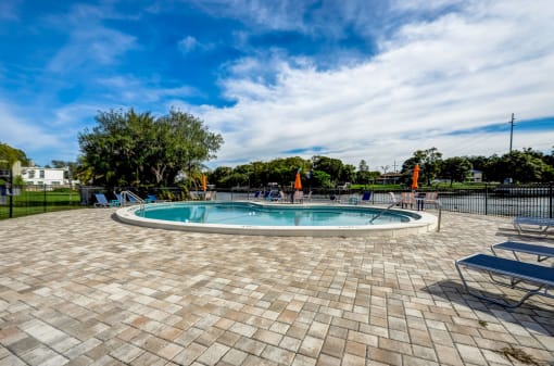 a swimming pool with blue skies and chairs around it
