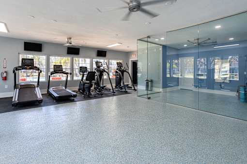 A gym with treadmills, exercise bikes, and a glass wall.