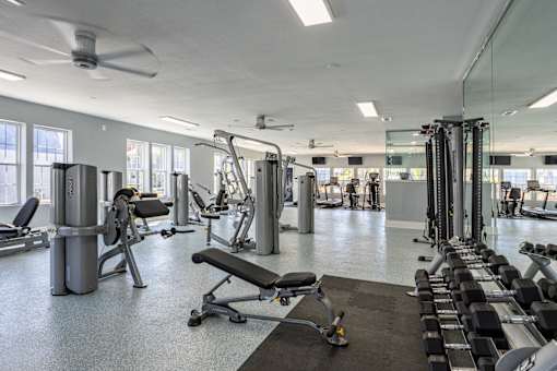 A spacious gym with a variety of equipment including treadmills, weights, and a bench press.
