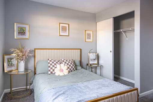 A bedroom with a bed, two side tables, and three framed pictures on the wall.