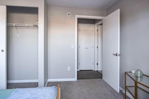 A bedroom with a bed, a wardrobe, and a small table.