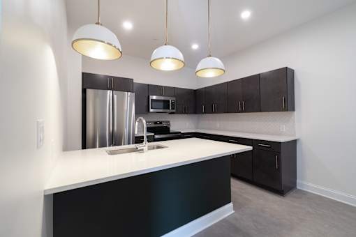 A kitchen with a white counter top and black cabinets.