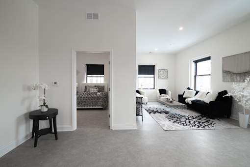 A living room with a black couch and a small table with a vase of flowers on it.
