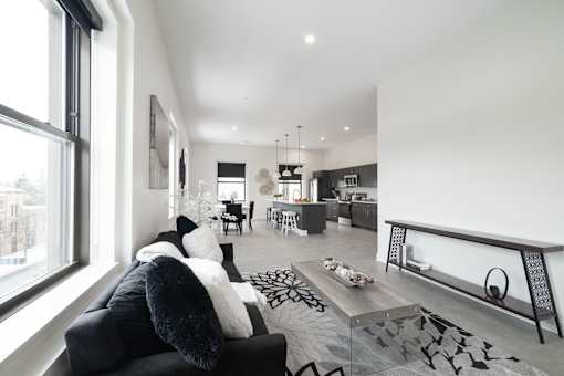 A modern living room with a black couch and a large window.