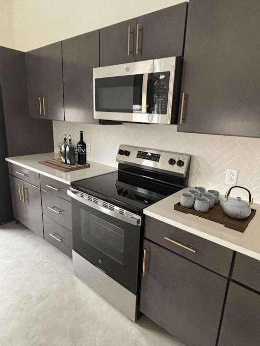 A modern kitchen with a stove top oven and microwave above it.