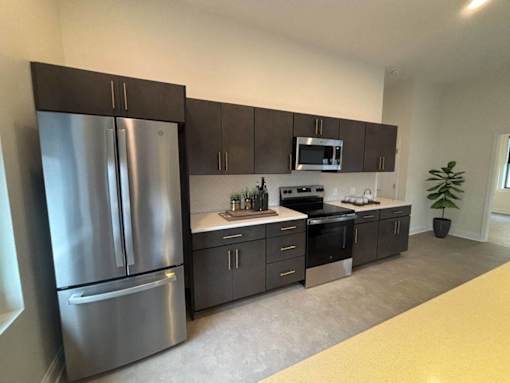 A modern kitchen with a stainless steel refrigerator and dark brown cabinets.