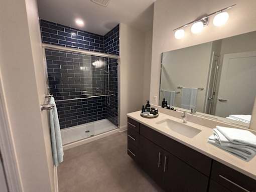 A bathroom with a white sink and a shower with a glass door.