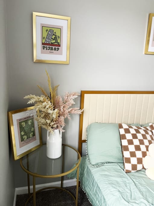 a bedroom with a bed and a table with a vase of flowers on itat Centerpointe Apartments, Canandaigua, NY
