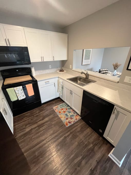a kitchen with white cabinets and black appliancesat Centerpointe Apartments, Canandaigua, New York