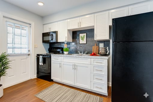 A kitchen with black appliances and white cabinets. at The Flats at Seminole Heights, Tampa, Florida