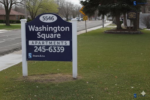 A sign for Washington Square Apartments is displayed in front of a tree.