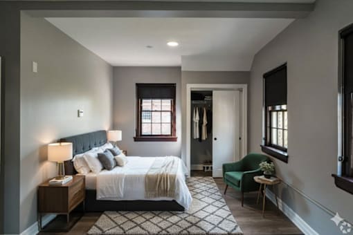 A bedroom with a large bed and a green chair.