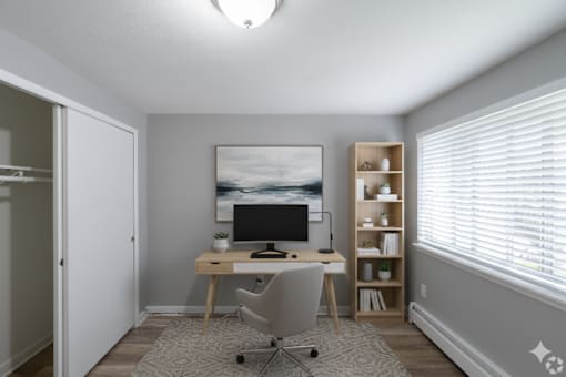 A room with a desk, chair, and a painting on the wall.