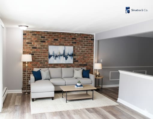 A living room with a brick wall and a white couch.