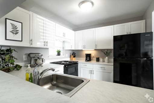 A modern kitchen with black appliances and white cabinets. at CenterPointe Apartments & Townhomes, Canandaigua, 14424