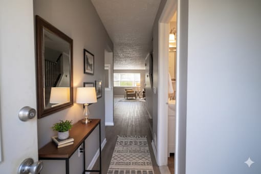 A hallway with a lamp and a plant on a table. at Willowbrooke Apartments & Townhomes, Brockport, 14420