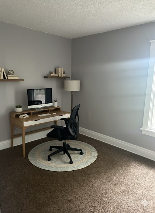 A black chair is in front of a desk with a computer on it.