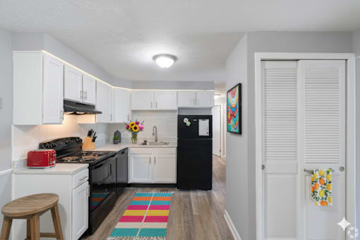 A kitchen with black appliances and white cabinets.