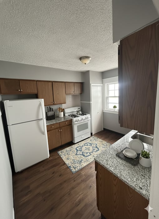 A kitchen with a white refrigerator and wooden cabinets.