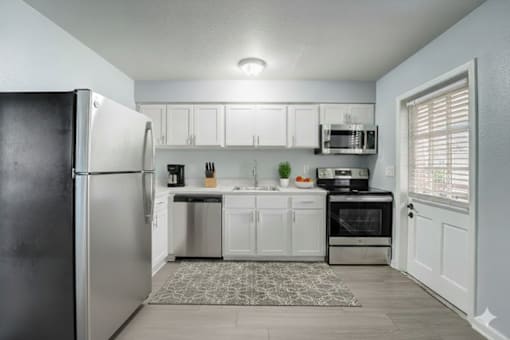 A kitchen with a black refrigerator and white cabinets. at The Flats at Seminole Heights, Tampa, FL, 33603