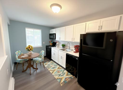 A kitchen with a black refrigerator and white cabinets. at Highview Manor Apartments, New York, 14450