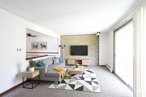 A living room with a grey couch and a black and white rug.