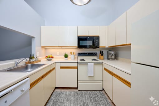 A small, modern kitchen with white appliances and cabinets. at CenterPointe Apartments & Townhomes, Canandaigua, 14424