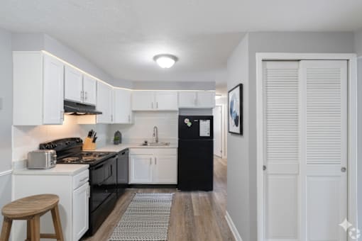 A kitchen with black appliances and white cabinets.